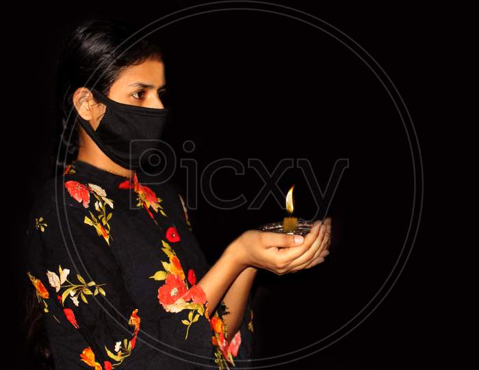 portrait of covid 19 infected sad woman hand holding burning candle for prayer  in dark background