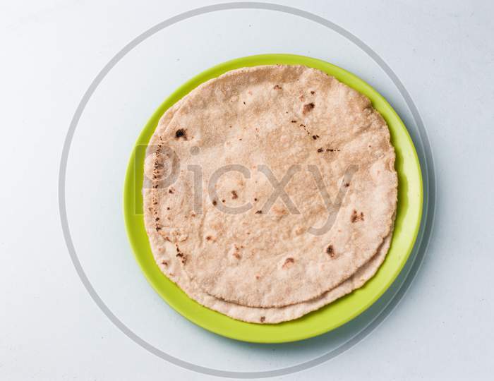 Chapati / Tava Roti/ Roti also known as Indian bread or Fulka/phulka. Main ingredient of lunch/dinner in India. decorated and served in a green colour plate isolated images.