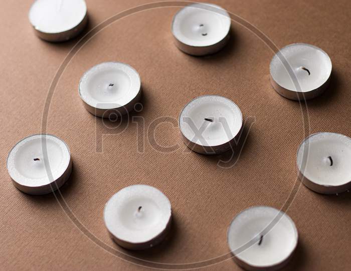 White candles isolated images with dark brown backdrop.