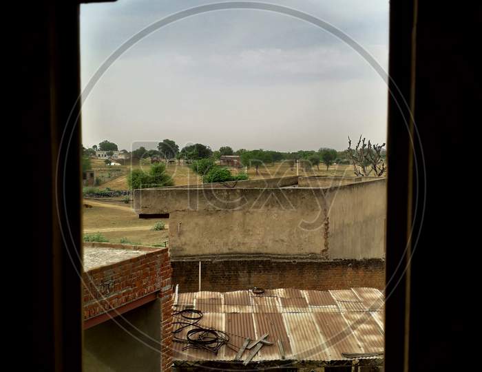 A beautiful view of a village outside from a wooden window