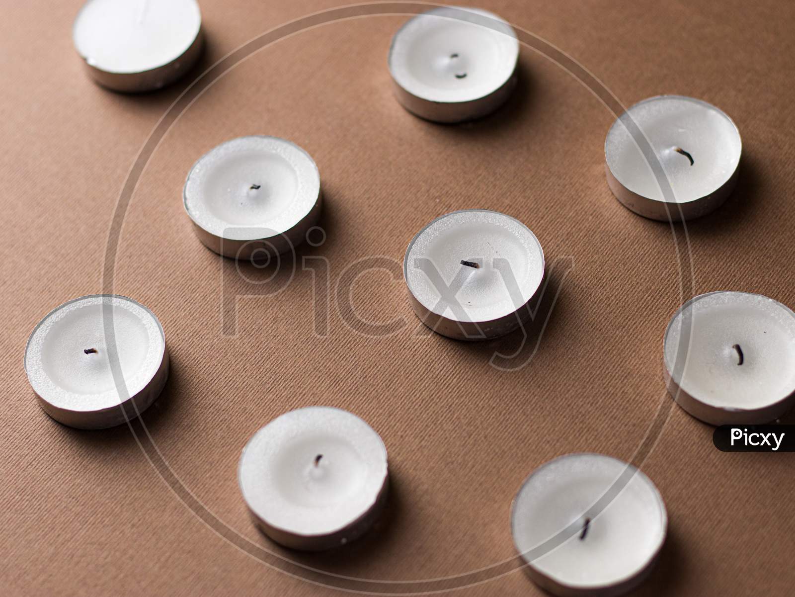 White candles isolated images with dark brown backdrop.