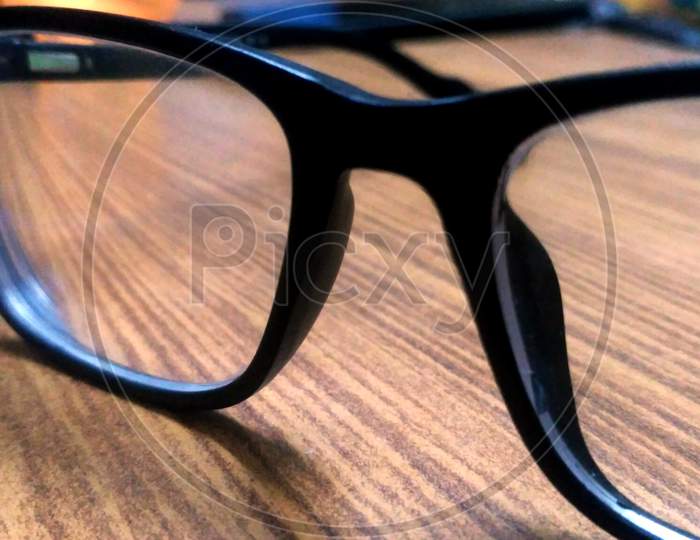 Glasses In Black Vintage Frame On Wooden Background, Table. View From Above.