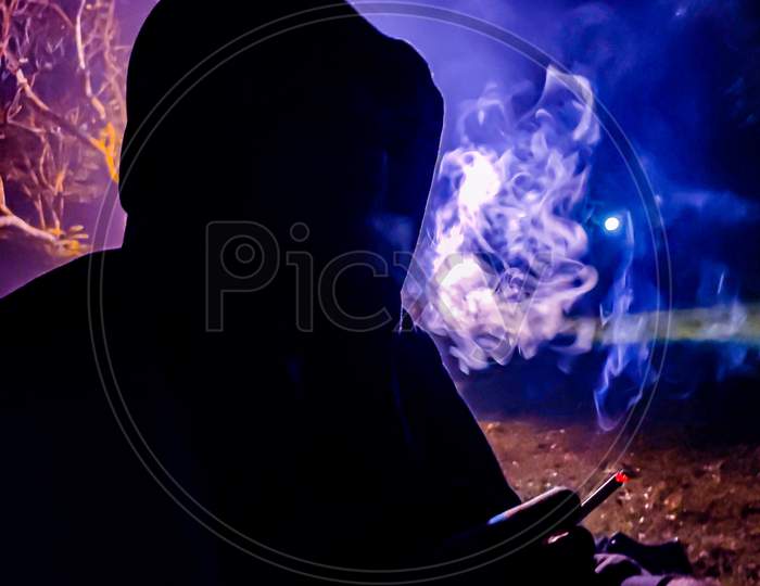 a man in black shadow smoking cigarette in the blue and purple background