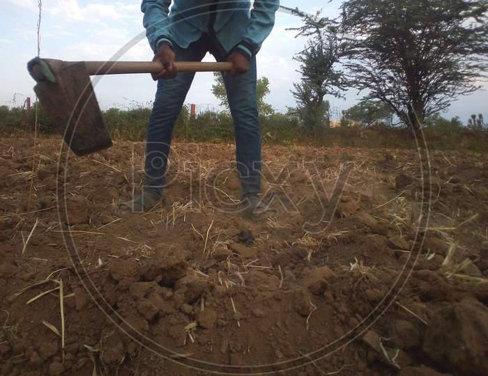 A Man Working at a Dried Agricultural Land With Tools