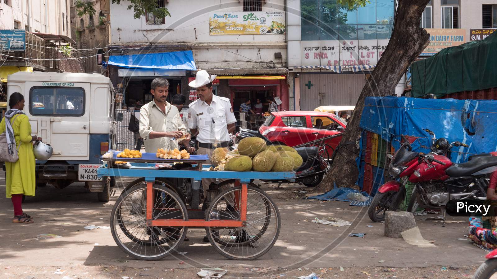 Bengaluru, Karnataka / India - March 15 2020: A traffic police checking the jackfruits sold by a street hawker near Russel market during daytime