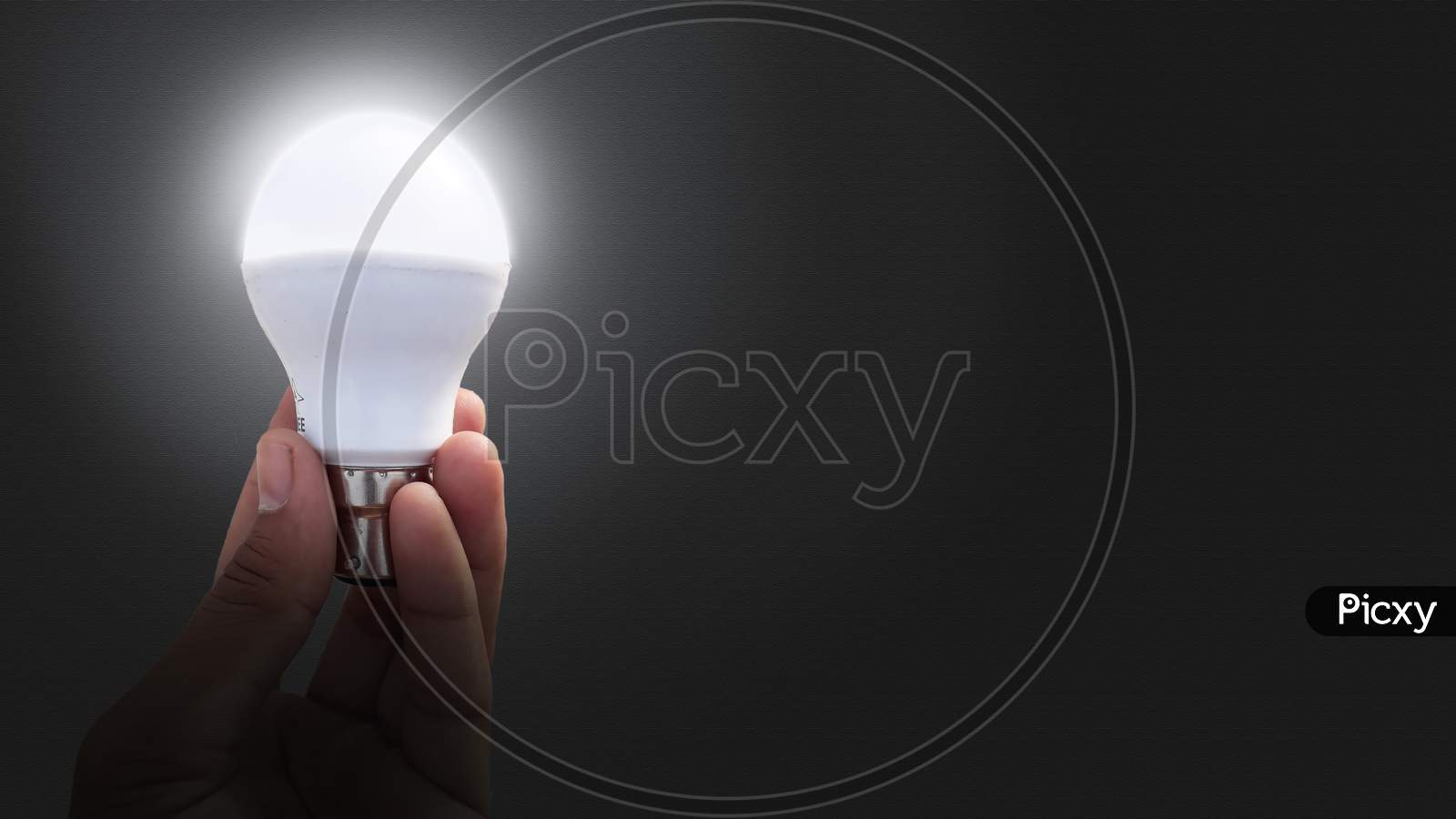 A white glowing LED bulb hold in hand on textured background / motivational background or image