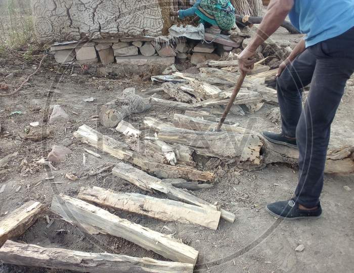 A Man Chopping Firewood With Axe In a Rural Indian Village