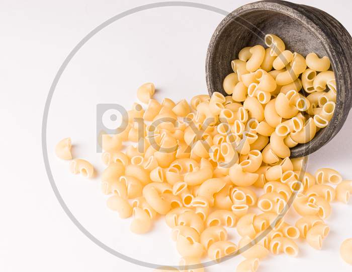 Uncooked macaroni elbow shape pasta with white background stock image.