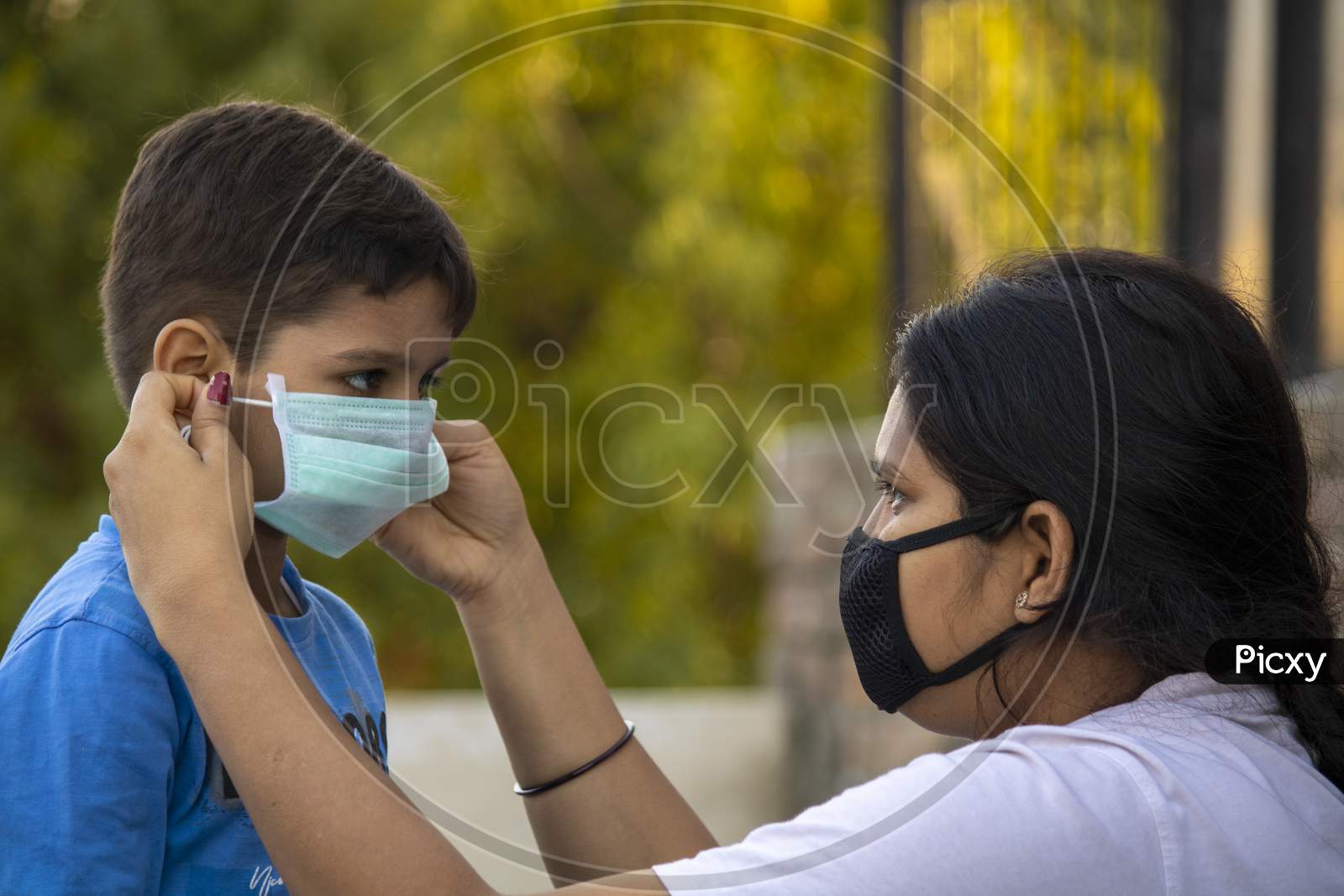 Mother Help Child To Wear Mask In India To Protect Him Against Flu And Virus