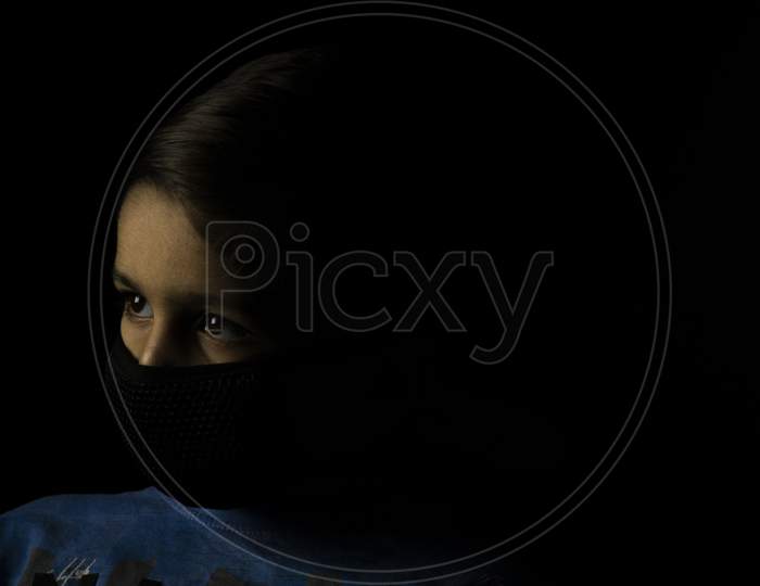 Low Key Photography Of Child With Mask On Face With A Space For Text