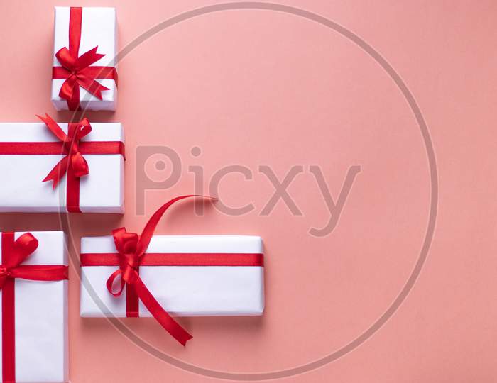 White gift box with red ribbon, black background flat lay for stock image