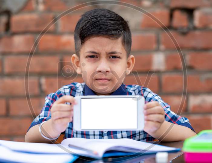 Little school kid learning from mobile , he is showing his mobile phone to the camera. Indian schools using latest technology for learning in schools.