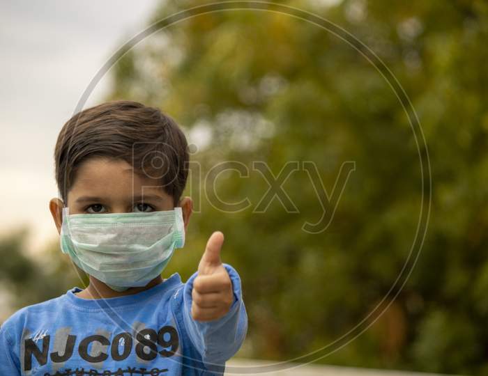 Indian Child With Mask Showing Thumbs Up During Corona Virus Lockdown Days In India