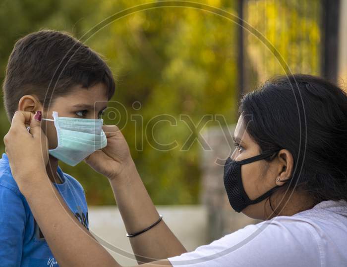 Mother Help Child To Wear Mask In India To Protect Him Against Flu And Virus