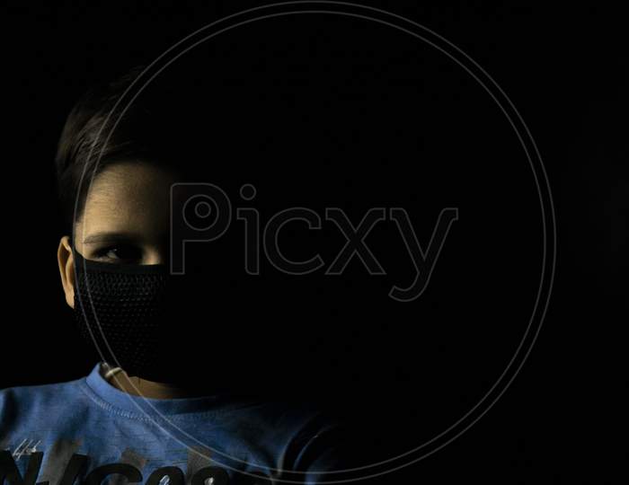 Low Key Photography Of Child With Mask On Face With A Space For Text