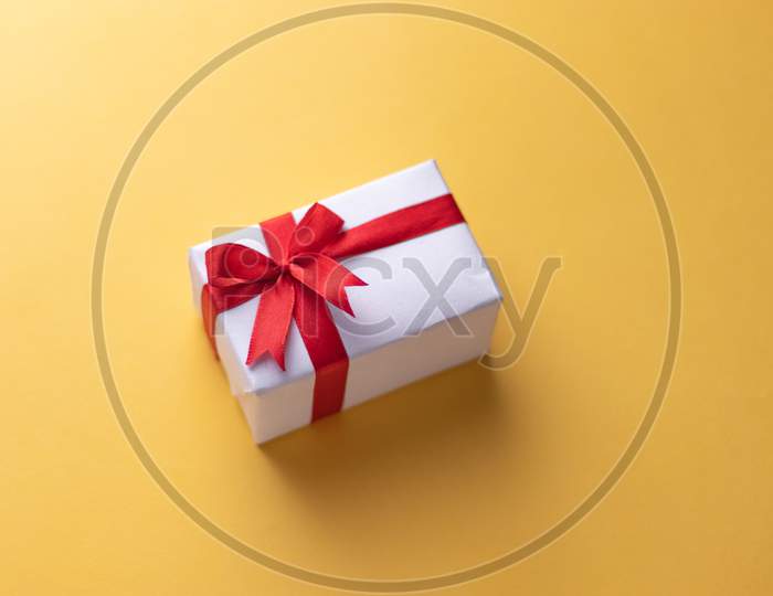 White gift box with red ribbon, black background flat lay for stock image
