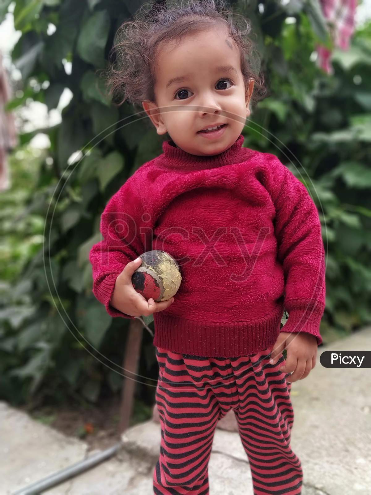 The very beautiful children with playing ball with green leaves background. Its a very beautiful and pretty child. its name is Vashu