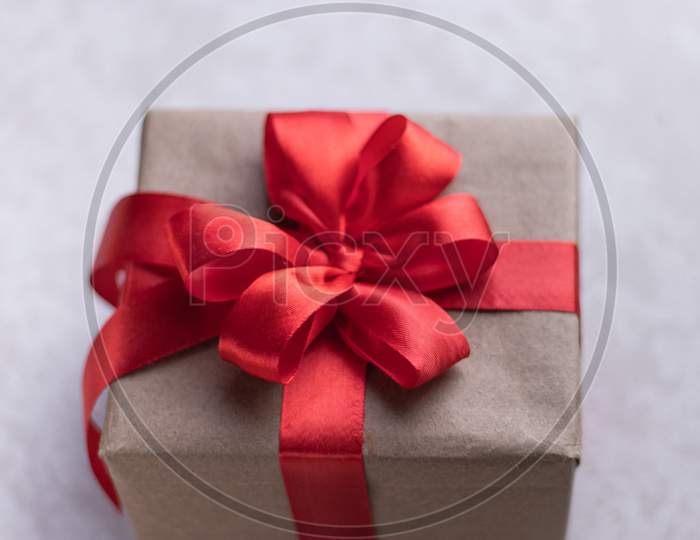 White gift box with red ribbon, white background flat lay for stock image