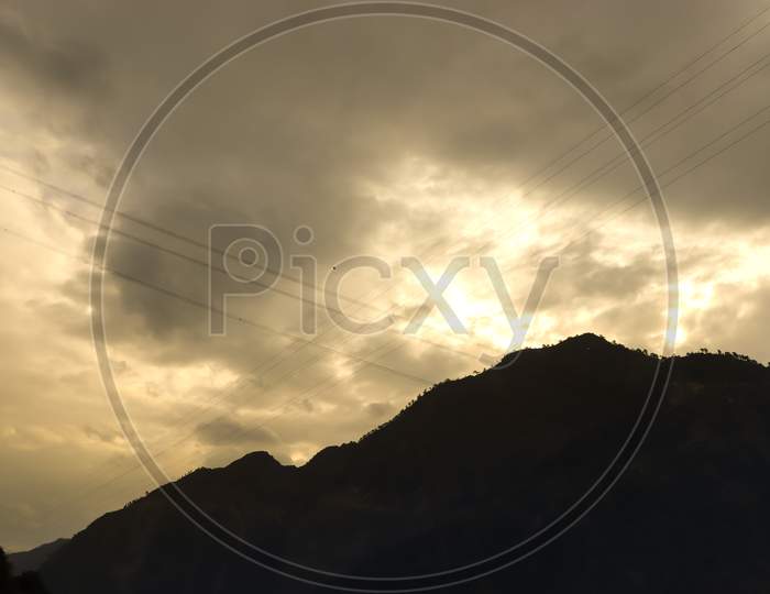 Yellow Clouds On The Background With A Mountain In Front. Silhouette
