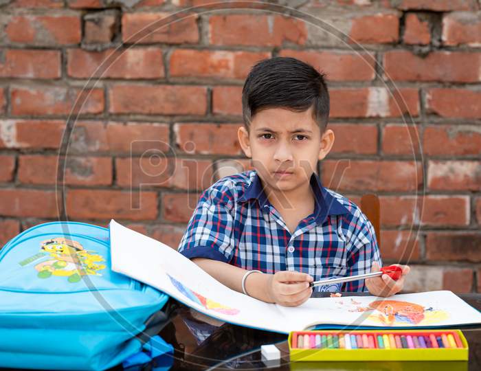 Indian schoolkid in uniform drawing and learning painting in classroom, Indian primary school education concept.
