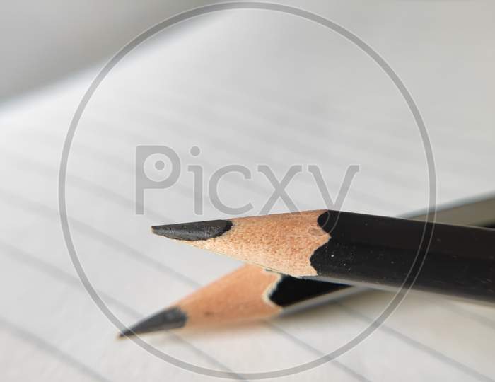 Pencil on white background. Pointed pencil on plain background. Pencil and sharpener on white paper. Pencil and straight line on paper.