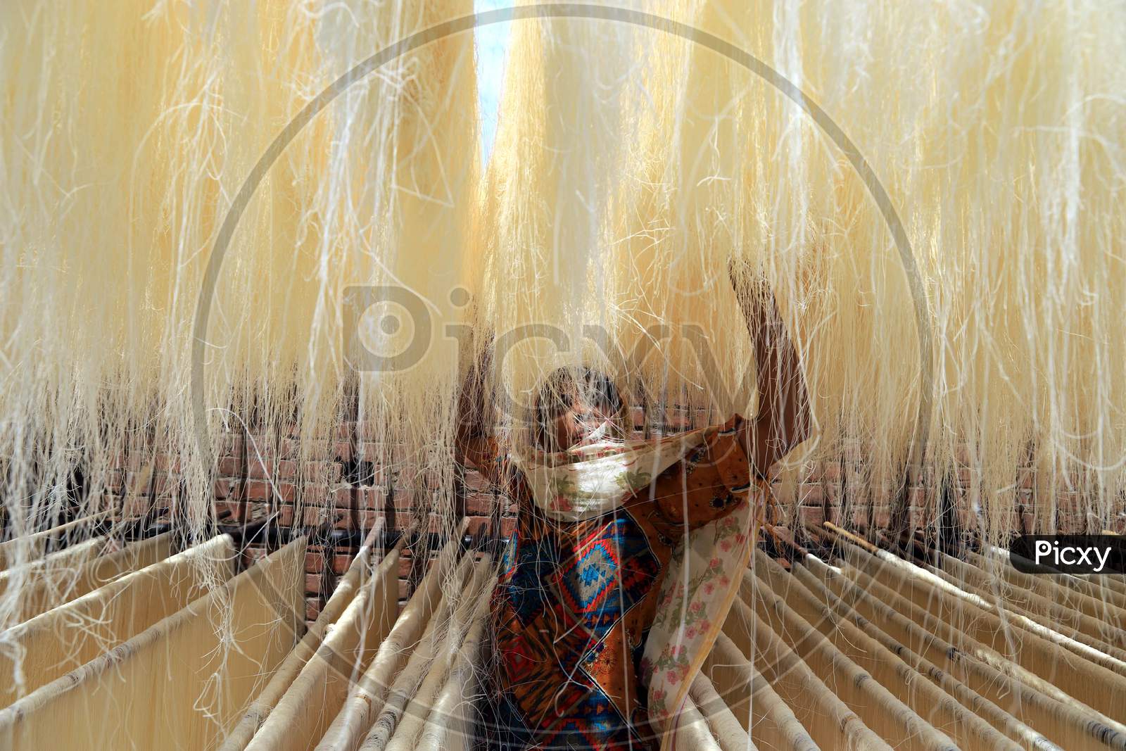 A woman spreads strands of vermicelli, a specialty eaten during the holy month of Ramadan, to dry it at a factory during a nationwide lockdown to slow the spreading of the coronavirus disease (COVID-19), in Prayagraj, April 28, 2020.