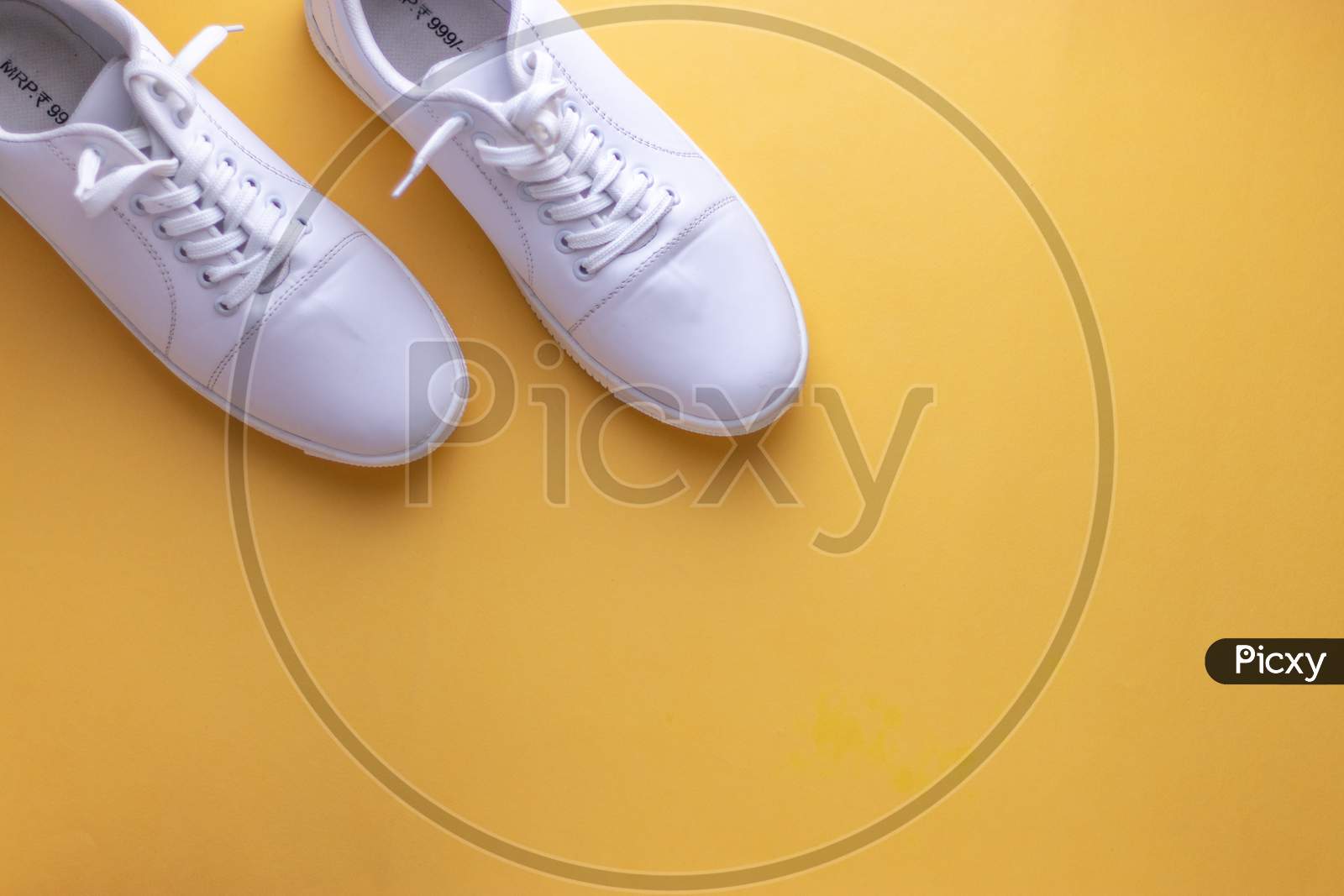 White sneakers on yellow colour background, flat lay top view minimal background.