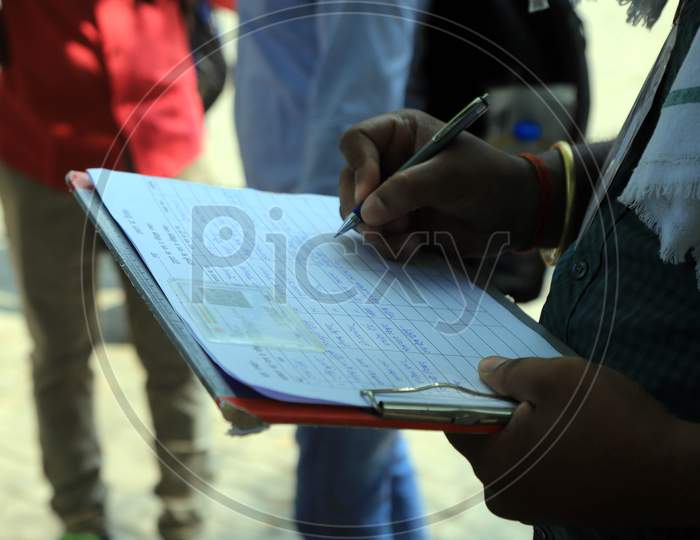 An employee in Prayagraj writes down details of students boarding the buses arranged by the Uttar Pradesh government to send them to their hometowns as a preventive measure against the COVID-19 in addition to the government imposed nationwide lockdown, April 28, 2020.