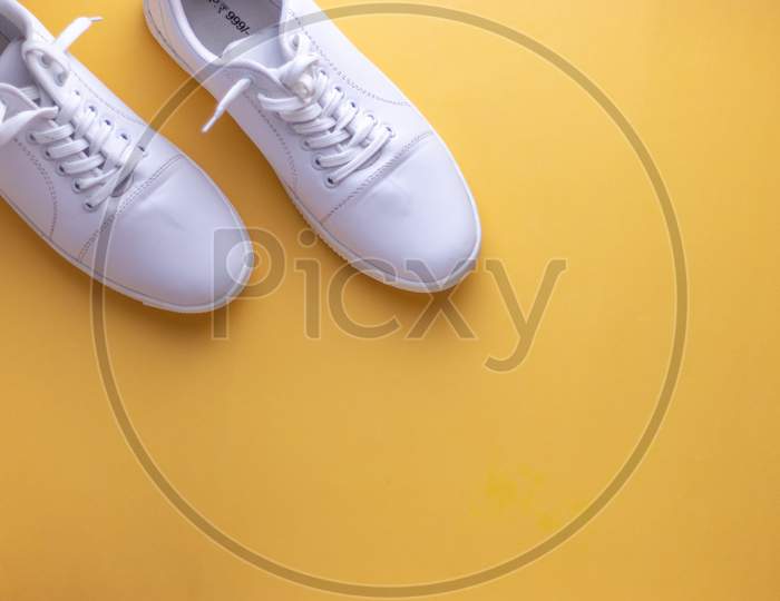 White sneakers on yellow colour background, flat lay top view minimal background.