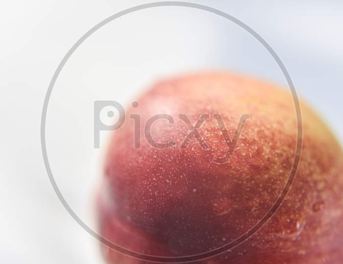 Red Skin Of The Peach With The Drop Of Water On It. White Background. Selective Focus