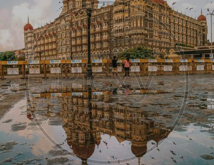 The Taj Palace of Mumbai city reflection with beautiful sky and birds flying