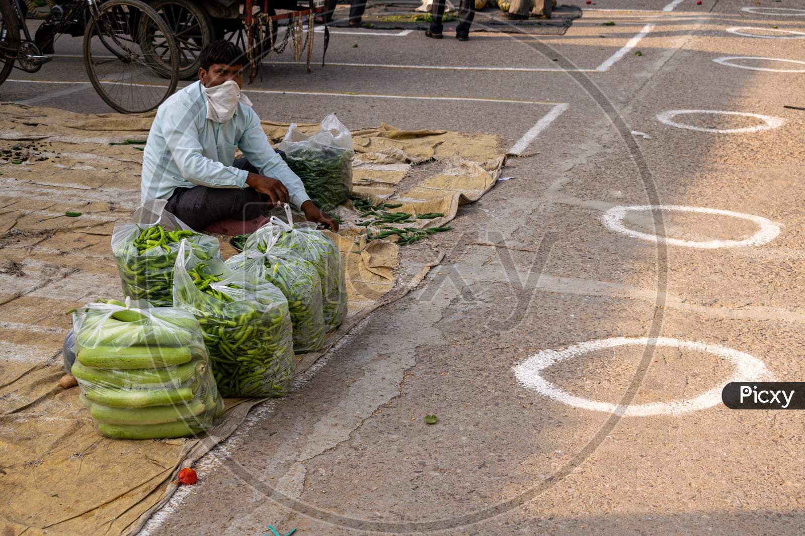 Vegetable sellers selling vegetables at Sabzi Mandi or vegetable market after partial exemption from lockdown and circles made on the ground for social distancing amid Coronavirus or Covid-19 outbreak in India