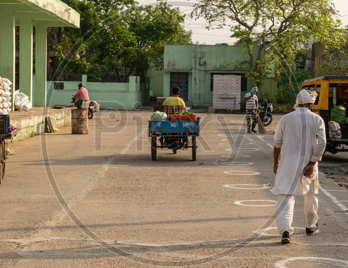 Vegetable buyer carrying vegetables on rickshaw at Sabzi Mandi or vegetable market after partial exemption from lockdown and circles made on the ground for social distancing due to Coronavirus or Covid1-19