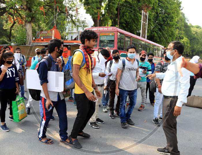 An officer checking identity card of students who had been stranded in the city for more than a month due to lockdown to prevent the spread of Coronavirus, board a specially scheduled bus to their respective hometowns, in Prayagraj.