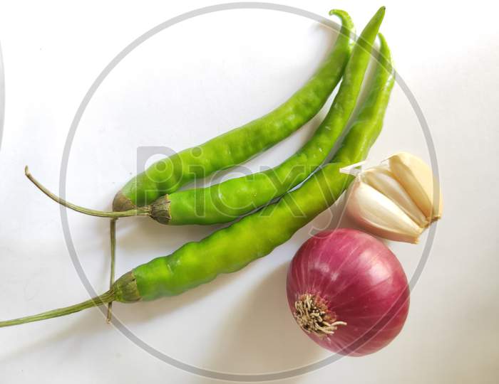 Onion and garlic and green chillies on white background. Kanda lasun mirchi photo. Fresh vegetables on plain background.