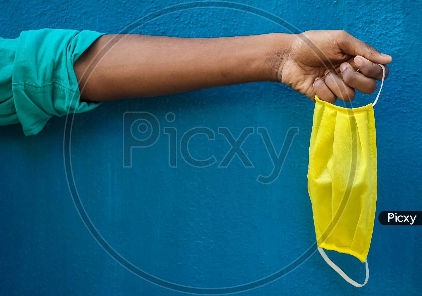 Man Holding Protective Yellow Face Mask Holding On His Hand Isolated On Blue Background