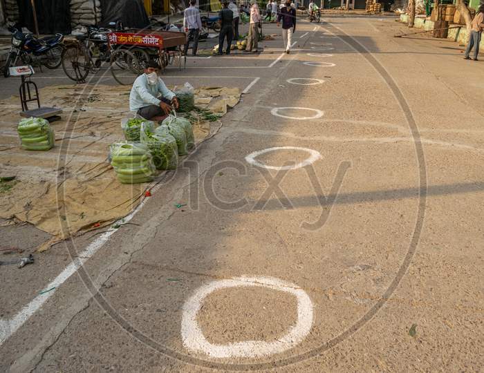 Vegetable sellers selling vegetables at Sabzi Mandi or vegetable market after partial exemption from lockdown and circles made on the ground for social distancing amid Coronavirus or Covid-19 outbreak in India