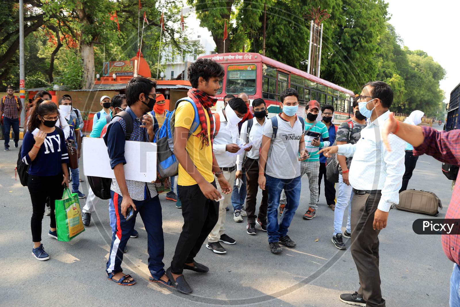 An officer checking identity card of students who had been stranded in the city for more than a month due to lockdown to prevent the spread of Coronavirus, board a specially scheduled bus to their respective hometowns, in Prayagraj.