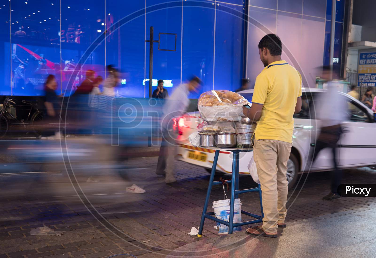 Bengaluru, Karnataka, India - November 08 2019: A man selling 'paani puri' a famous Indian snack on the road ride and people in the background in motion blur during evening