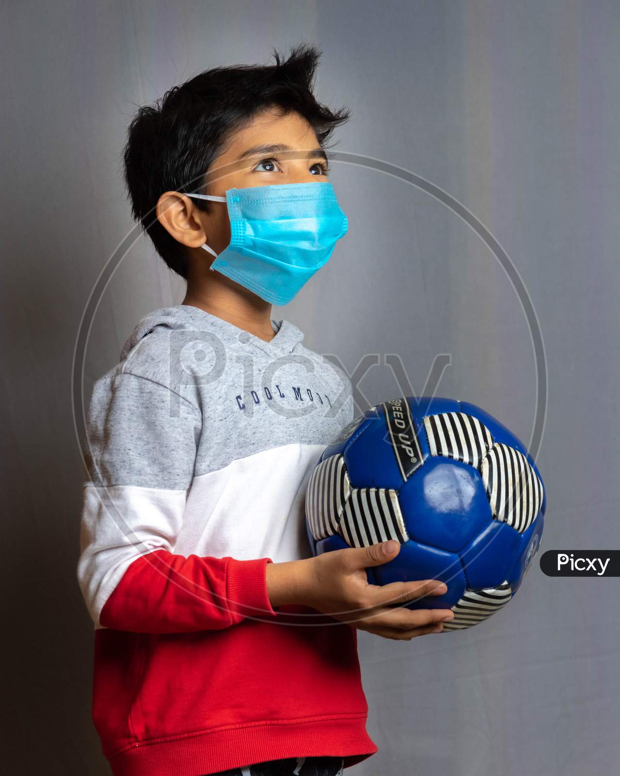 Portrait of a boy wearing mask and playing soccer inside home during CoronaVirus Lockdown. Stay home, stay safe.