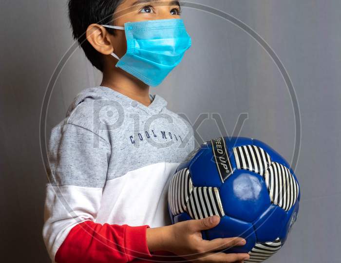 Portrait of a boy wearing mask and playing soccer inside home during CoronaVirus Lockdown. Stay home, stay safe.