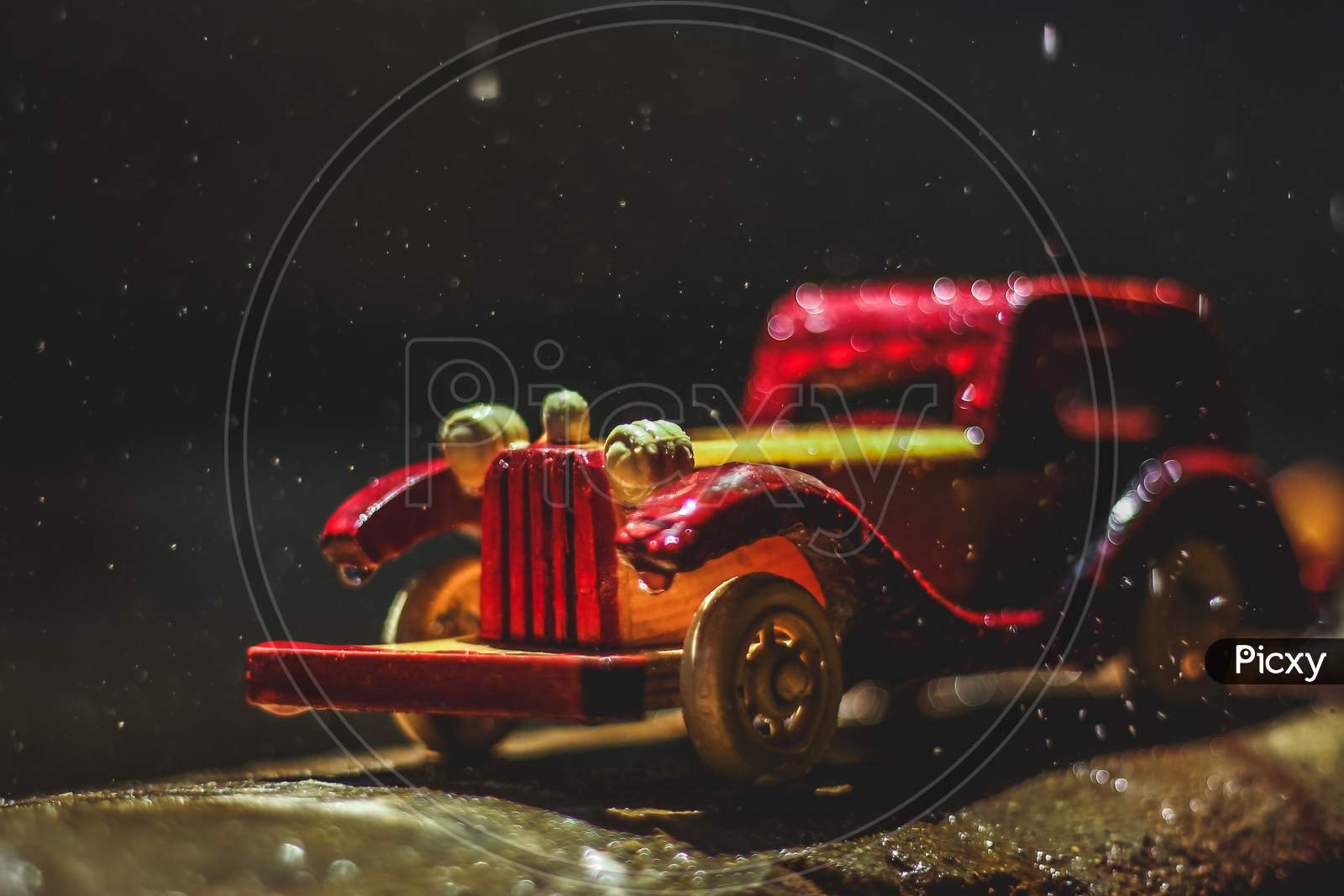 Vintage Toy Car Under The Rain On The Road. Miniature Car Toy In Rain. Red And Yellow Vintage Car On Rain. Rain Falling On Vintage Car Toy Close Up