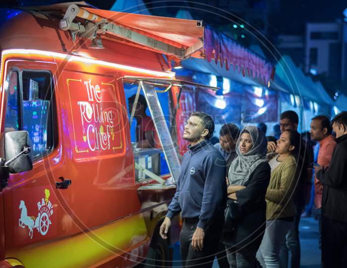 Bangalore, Karnataka / India - August 08 2019: A group of people waiting outside a red food truck for their orders during night time
