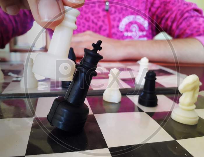 A girl is playing chess and winning the match by beating opponent king