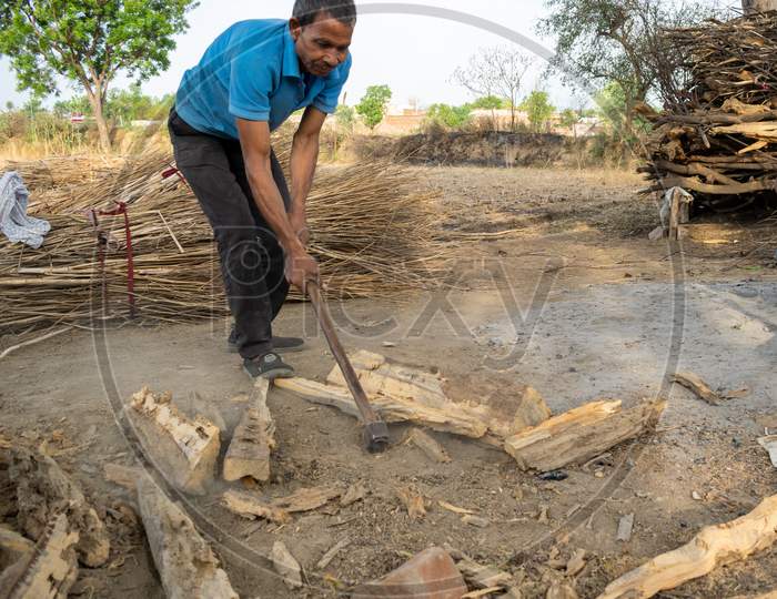 A man cutting dry woods in small pieces using axe