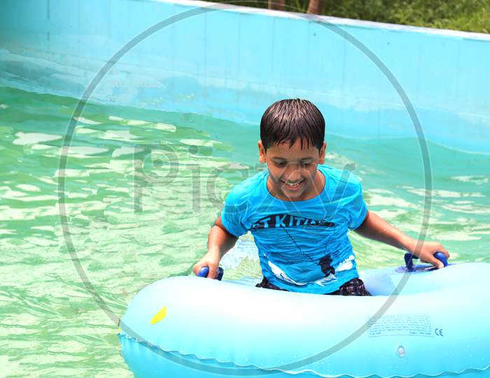 A school boy is enojying at the swimming pool water, very enjoyable moment