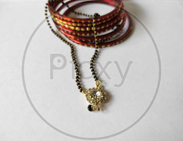 Necklace and bangles on white background. Mangalsutra and bangles on plain background. Traditional ornaments close up view.