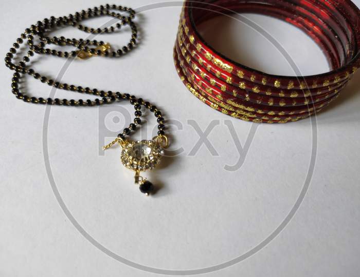 Necklace and bangles on white background. Mangalsutra and bangles on plain background. Traditional ornaments close up view.