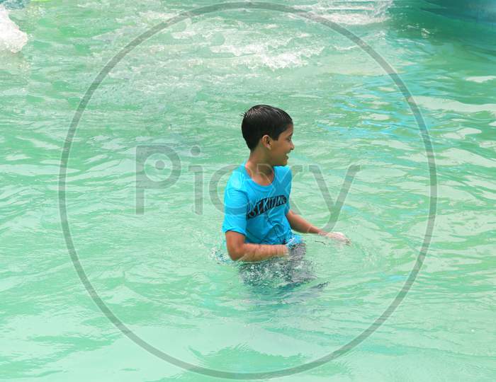 A school boy is enjoying at the swimming pool water, very enjoyable moment