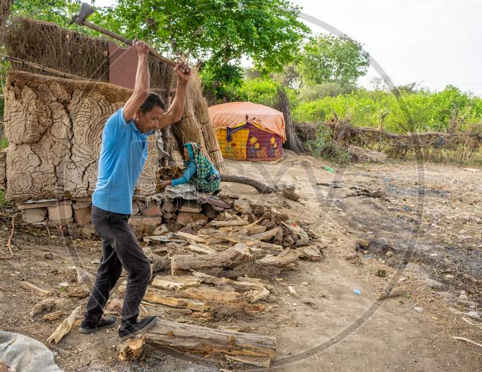 A man cutting dry woods in small pieces using axe